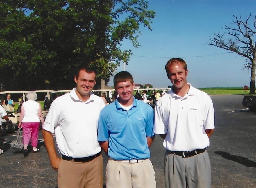 A group photo of 3 men smiling for the camera at the parking lot.